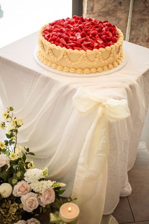 A beautiful raspberry tart dessert displayed on a white tablecloth with delicate roses and candles.
