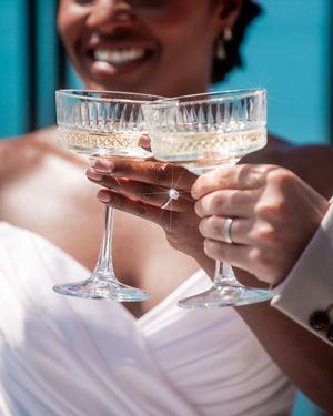 Elegant crystal champagne glasses being held during a wedding toast.