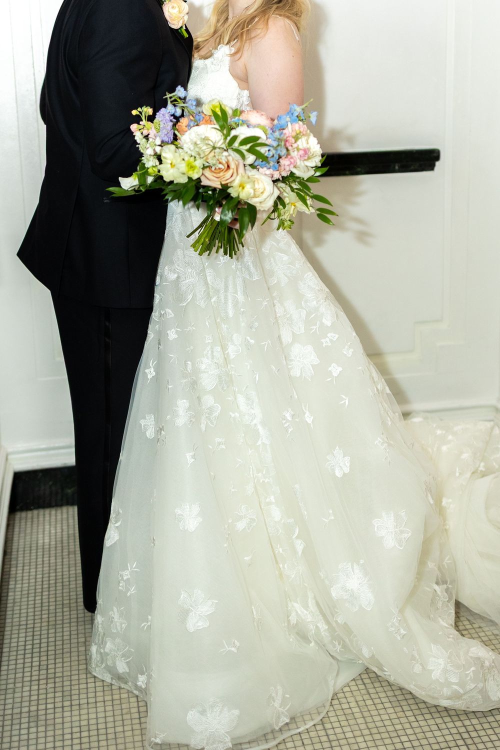 A bride in a white lace wedding gown holds a delicate bouquet of pink and white flowers during a ceremony.  NASHVILLE WEDDING PHOTOGRAPHER