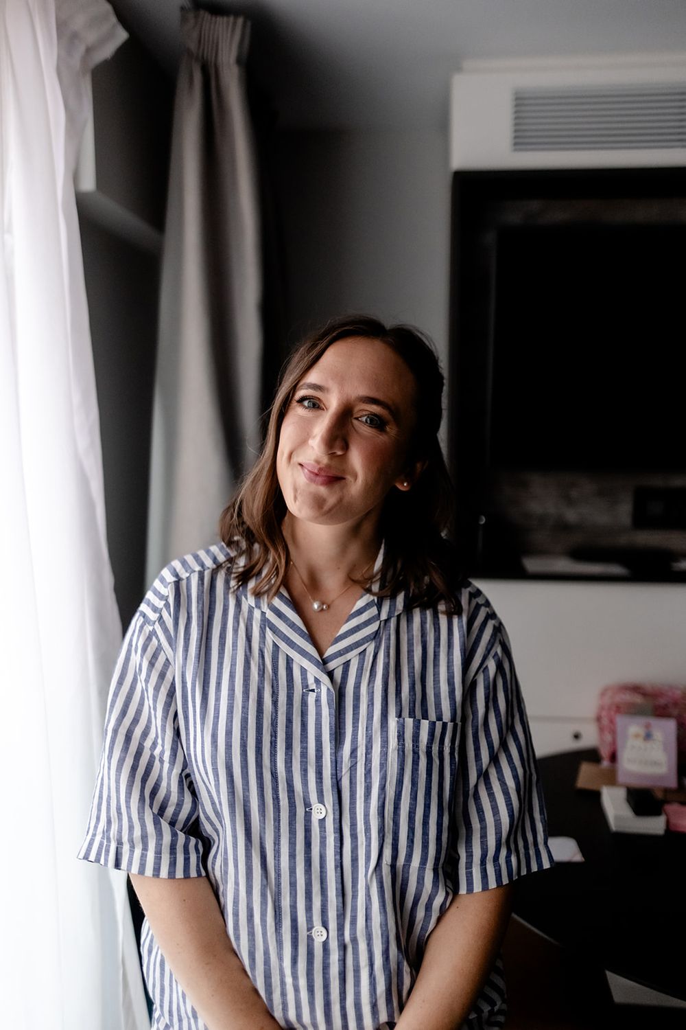 Person wearing blue and white striped button-up shirt in natural window light.
