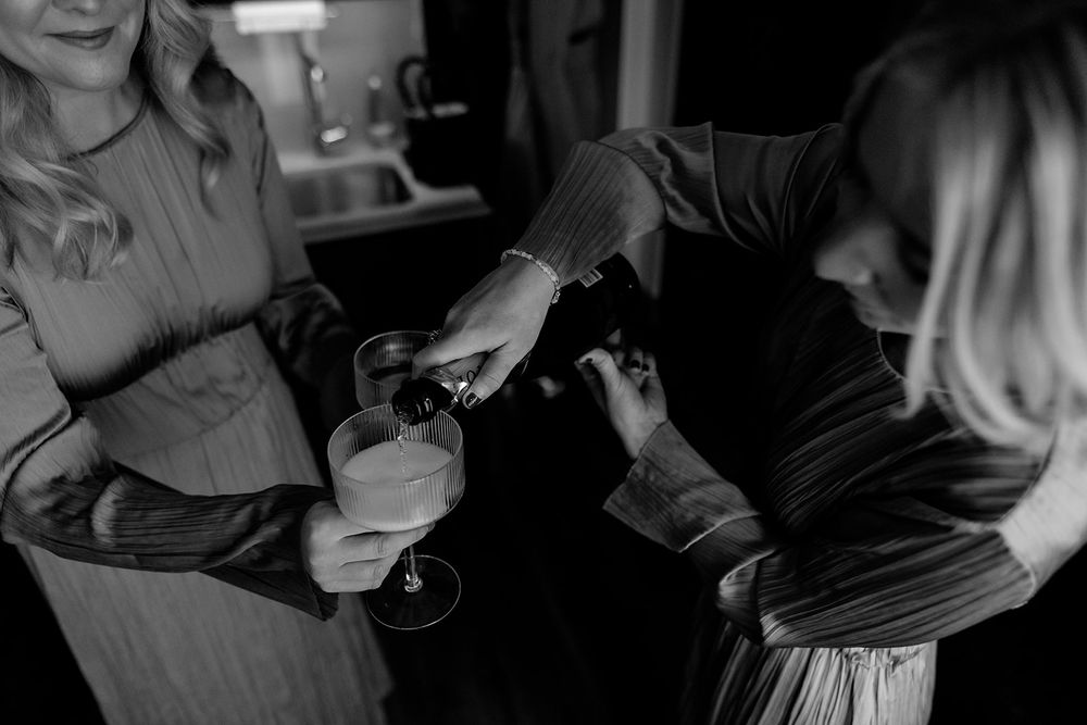 Hands preparing wedding details in dramatic black and white lighting.