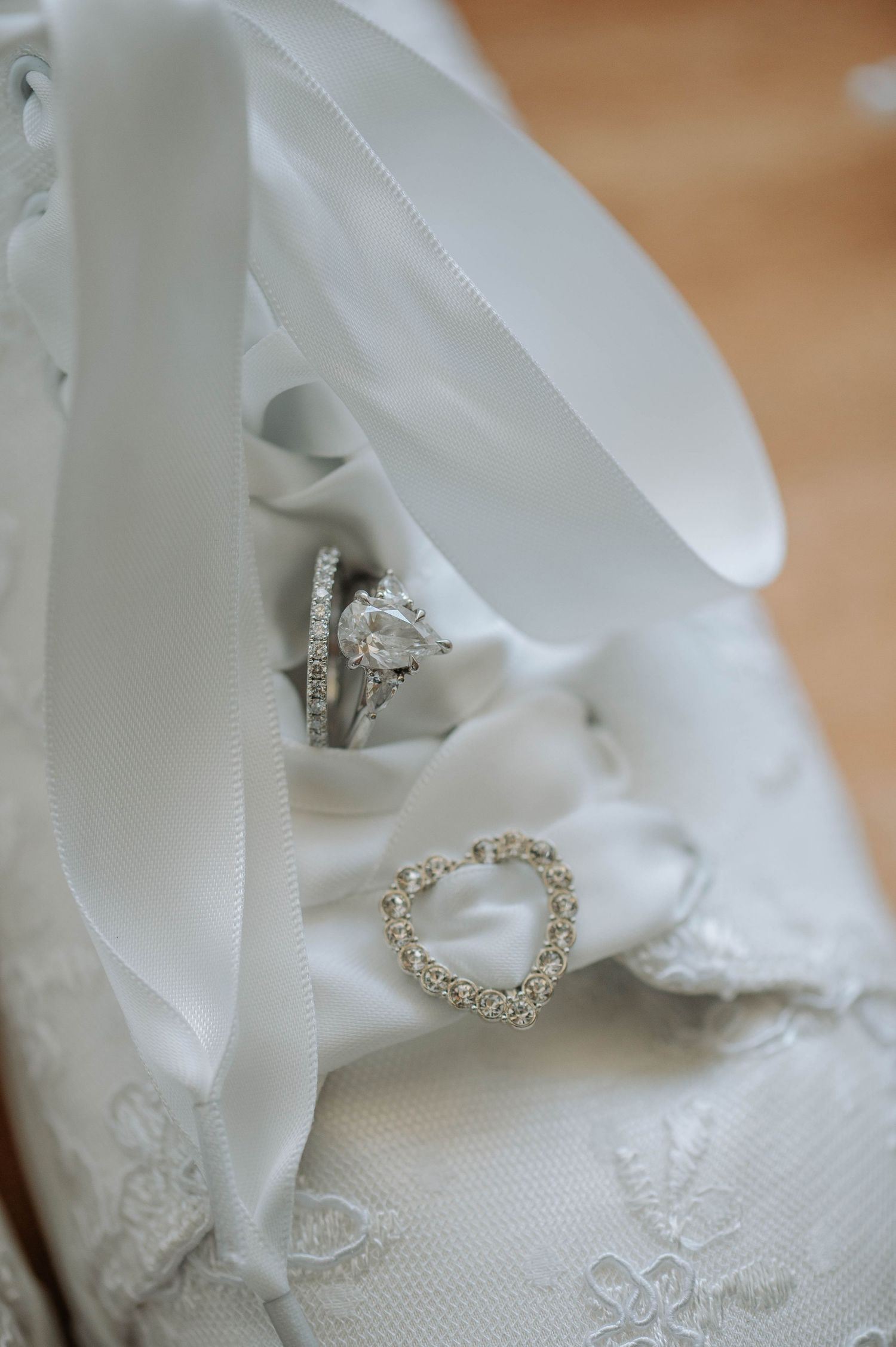 Diamond engagement ring nestled in white lace and satin ribbon details in an elegant wedding setting.