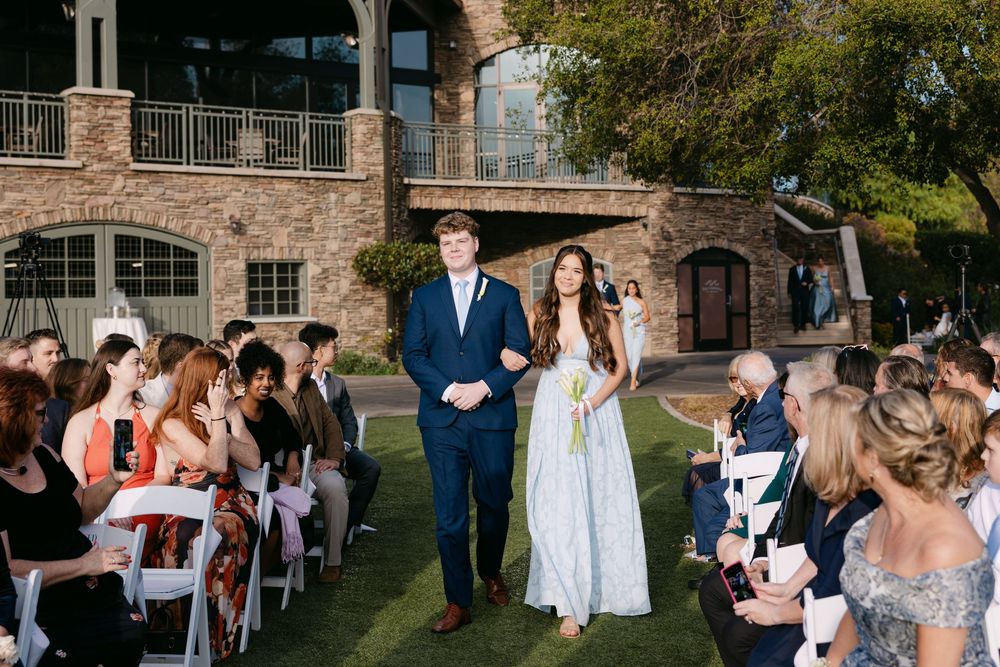 Panoramic view of wedding guests seated in rows during an outdoor ceremony at a historic brick venue.