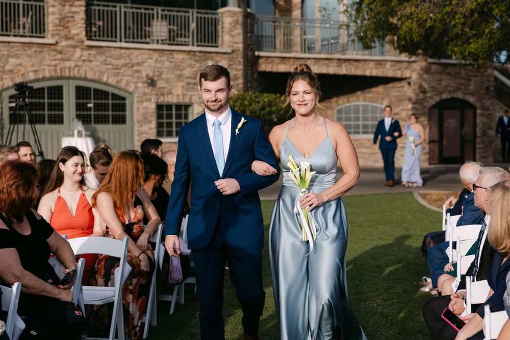 Wedding guests gather outdoors at a rustic brick venue during an elegant ceremony celebration.