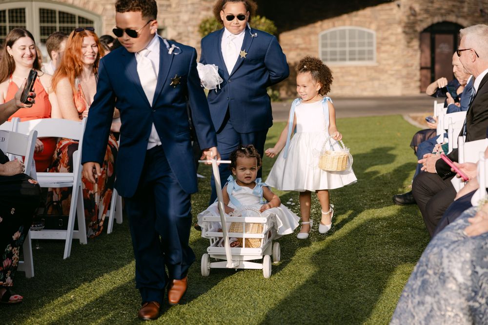 Guests celebrate during an outdoor wedding reception on a grassy lawn near a brick building.