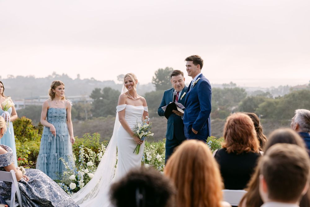Scenic outdoor wedding ceremony overlooking rolling hills and mountains at sunset.