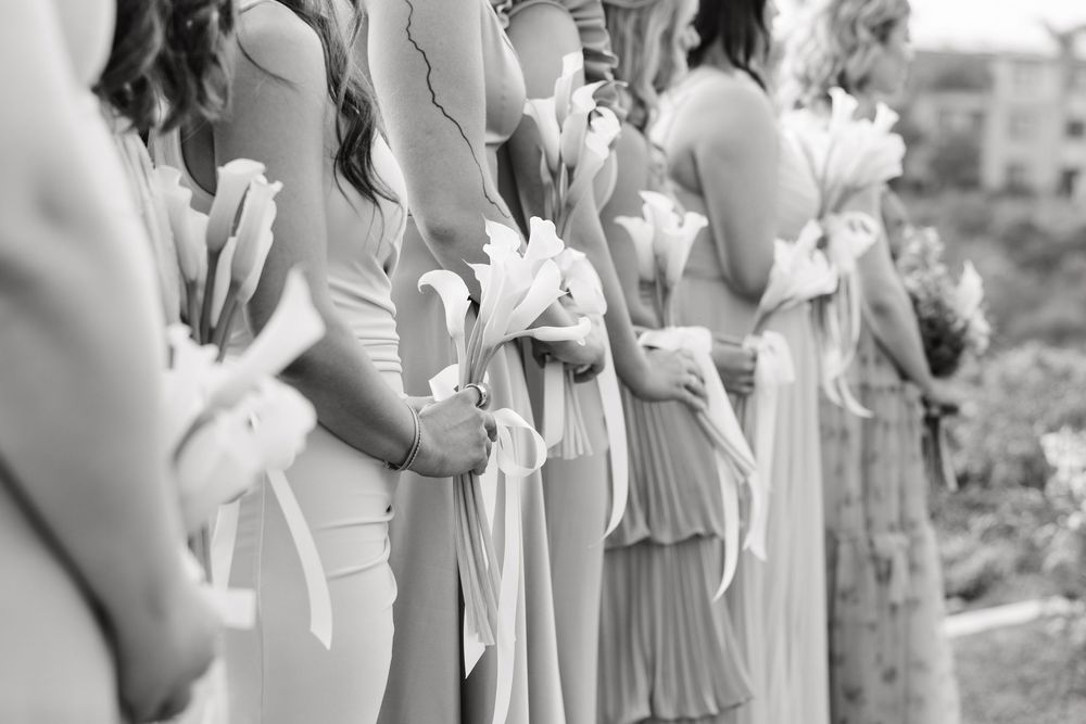 Wedding ceremony attendees stand in a row wearing coordinated light blue dresses against a natural backdrop.