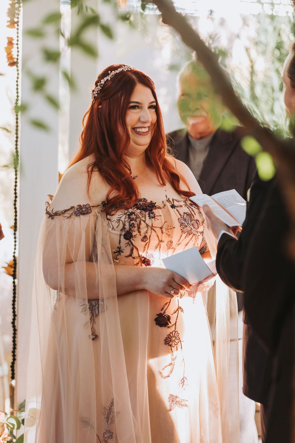 A romantic wedding ceremony moment with flowing white fabric and floral decorations in an intimate indoor setting.