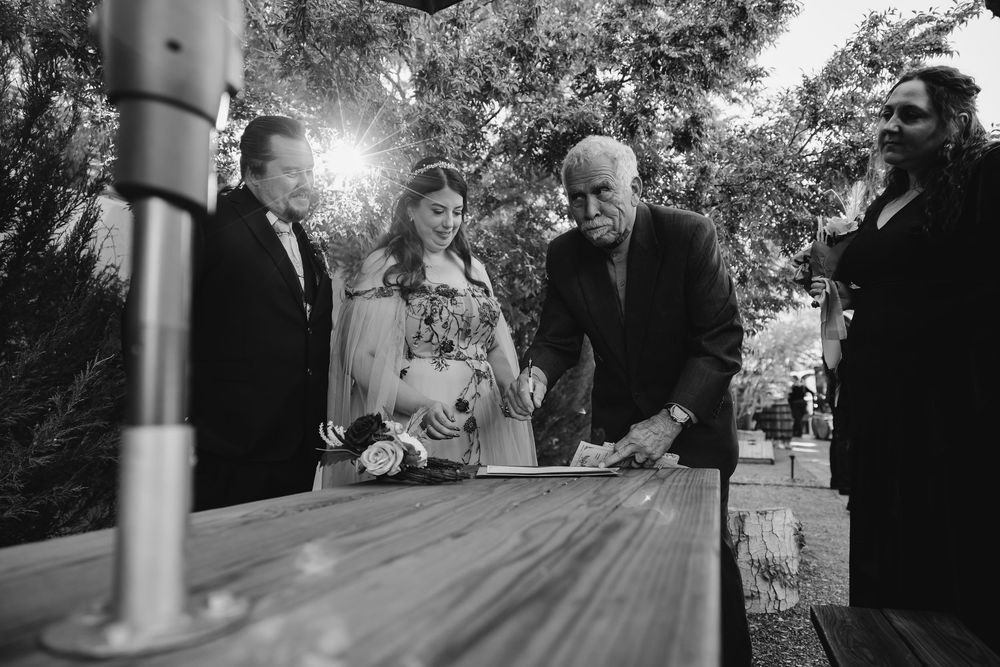 Black and white photo of a small group gathered around an outdoor table during a celebration in a garden setting.