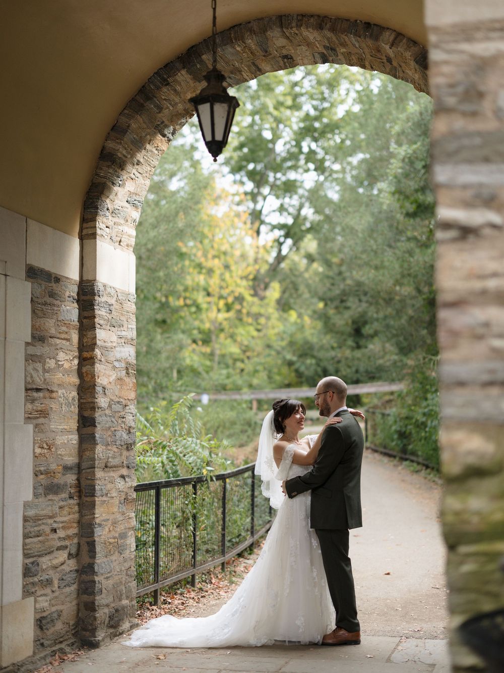 Couple shares romantic moments in front of glass conservatory greenhouse during autumn wedding photoshoot.