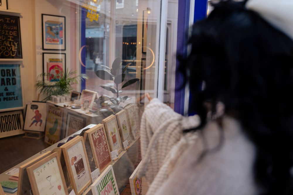 A gallery wall displays multiple framed artworks and posters in a well-lit interior space.