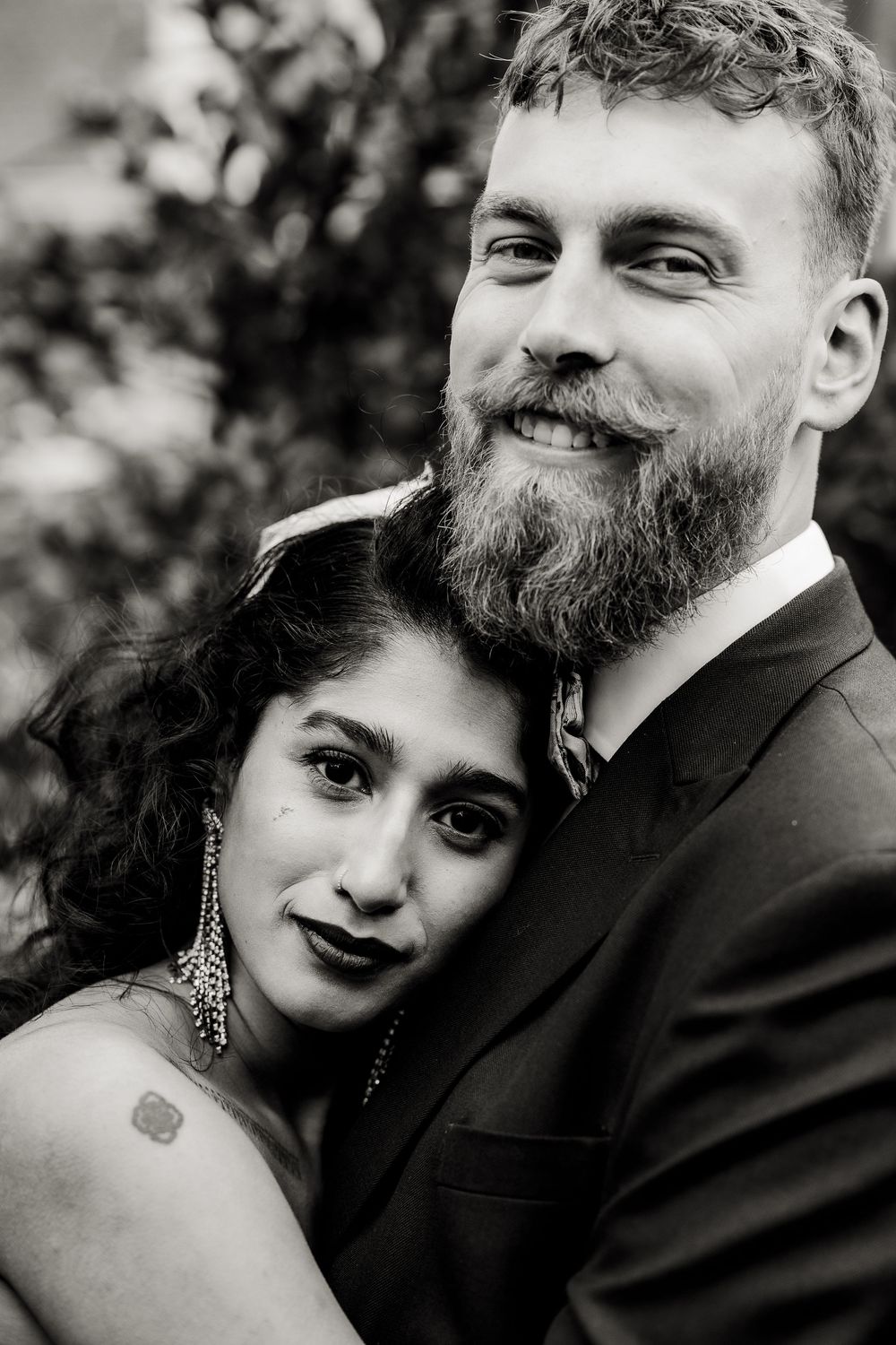A romantic black and white portrait series showing a couple embracing in an intimate outdoor setting.