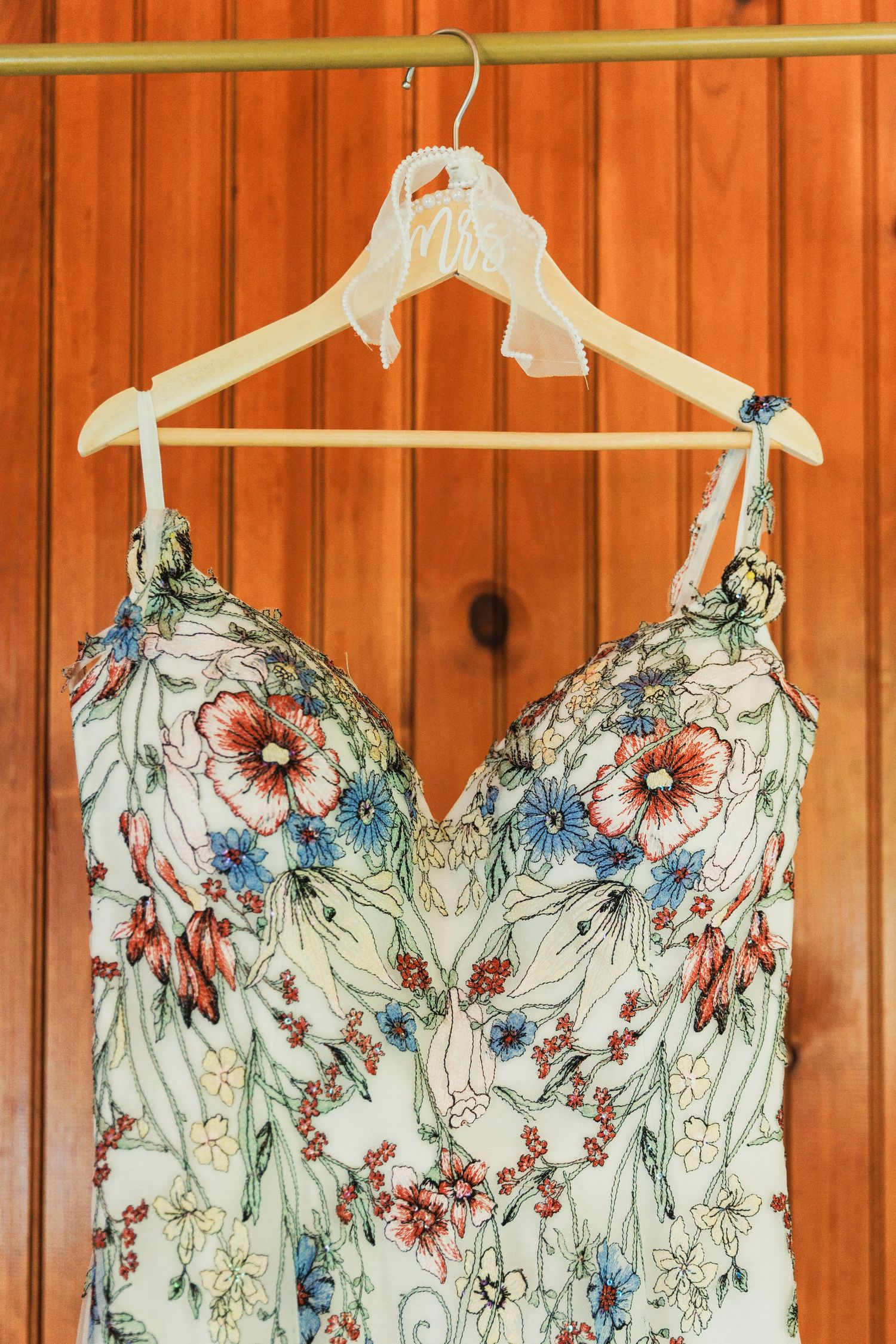 Floral wedding dress details showing delicate pink and blue flower embroidery.