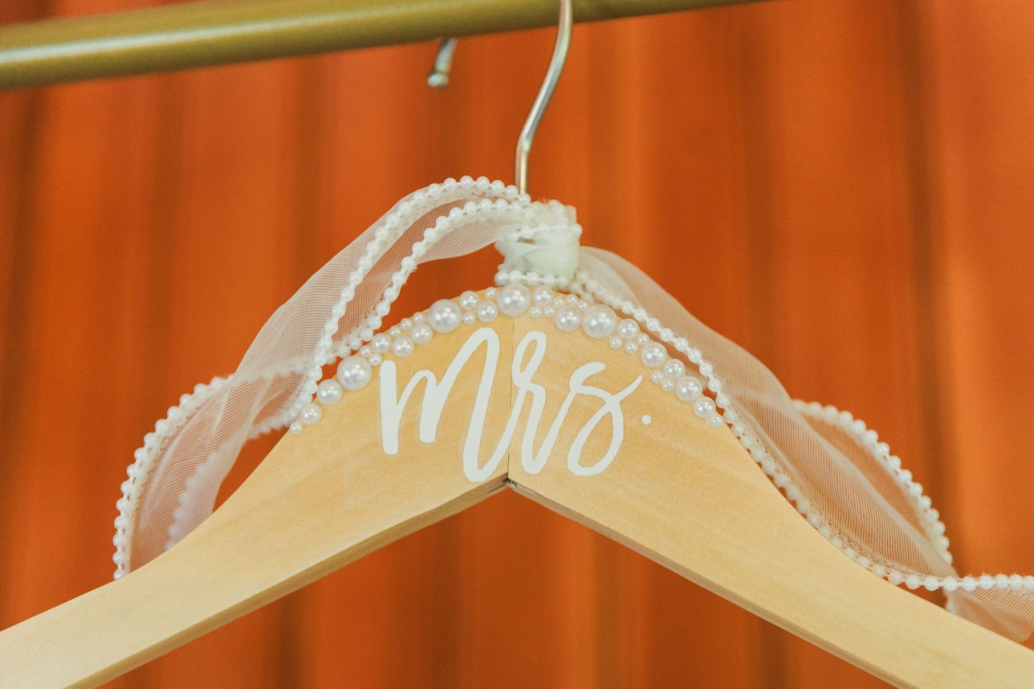 Wedding dress hangers with custom text displayed against orange background.