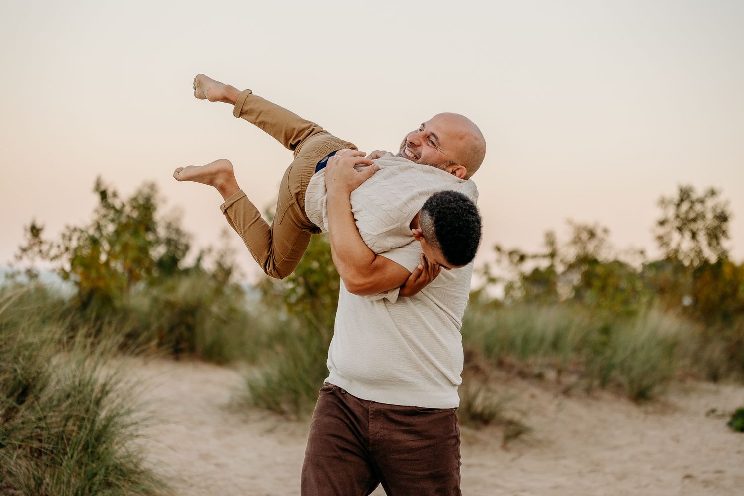 Father lifting child during golden hour family beach photography in Chicago
