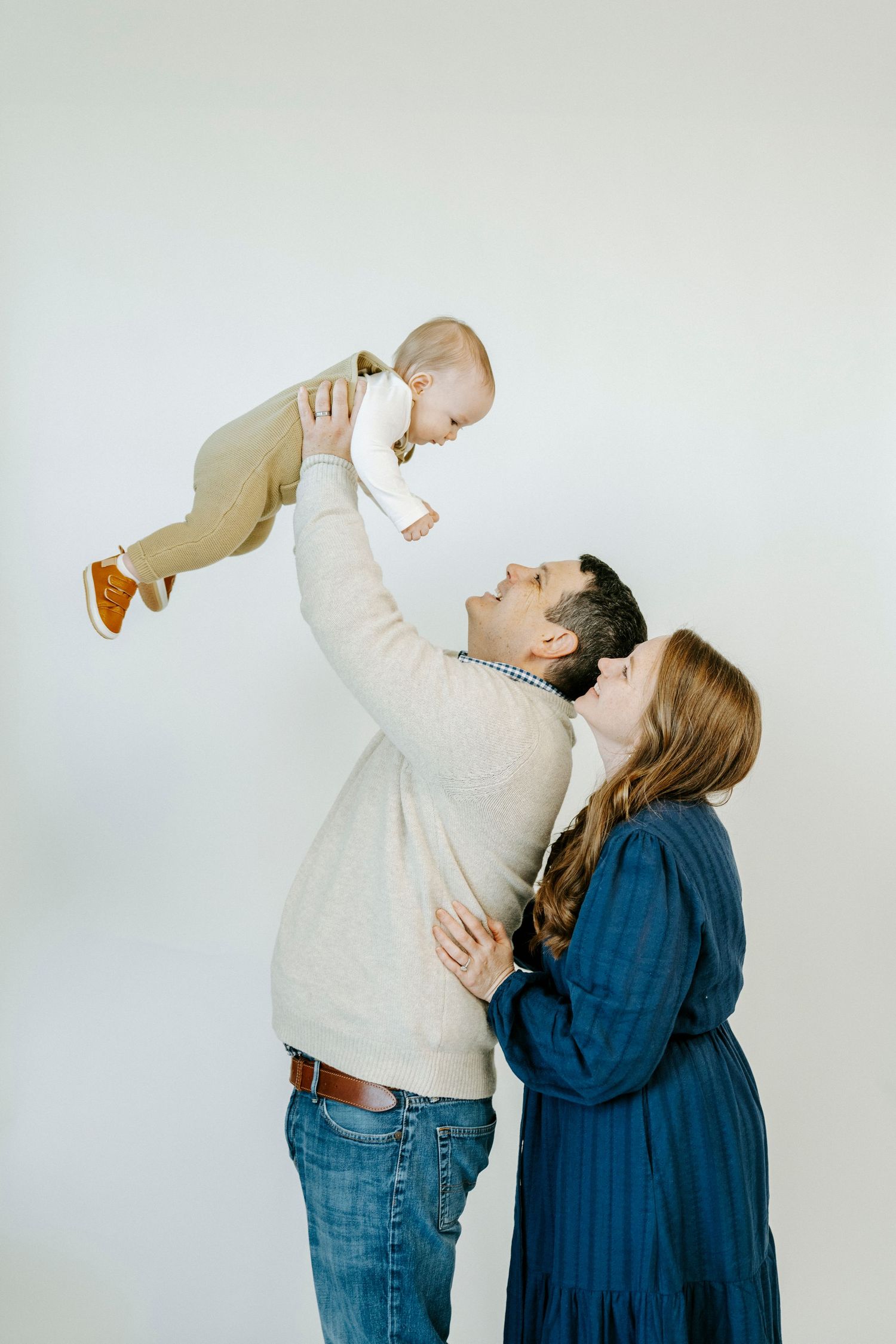 A couple in jeans and sweaters playfully pose together against a white background in a sequence of four photos.