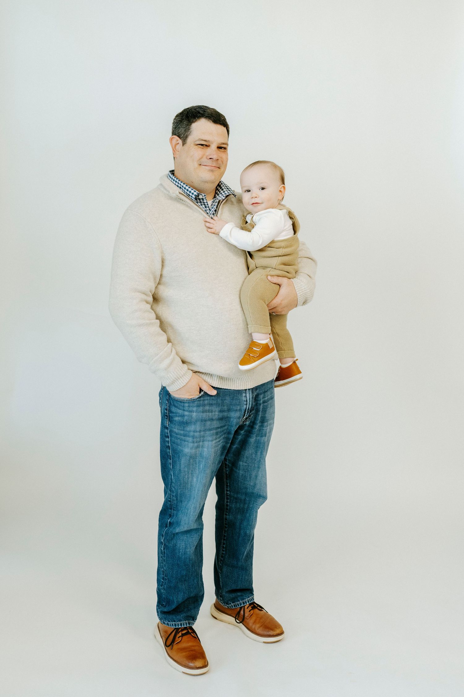 A person wearing a beige sweater and jeans holds a baby against a white background in three similar poses.