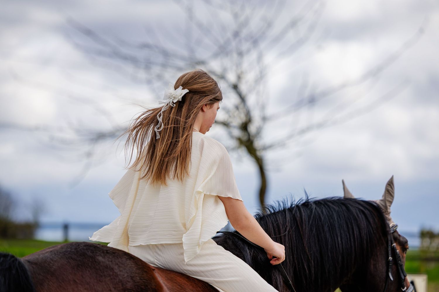 A horse and rider silhouetted against cloudy sky during an outdoor photo session.