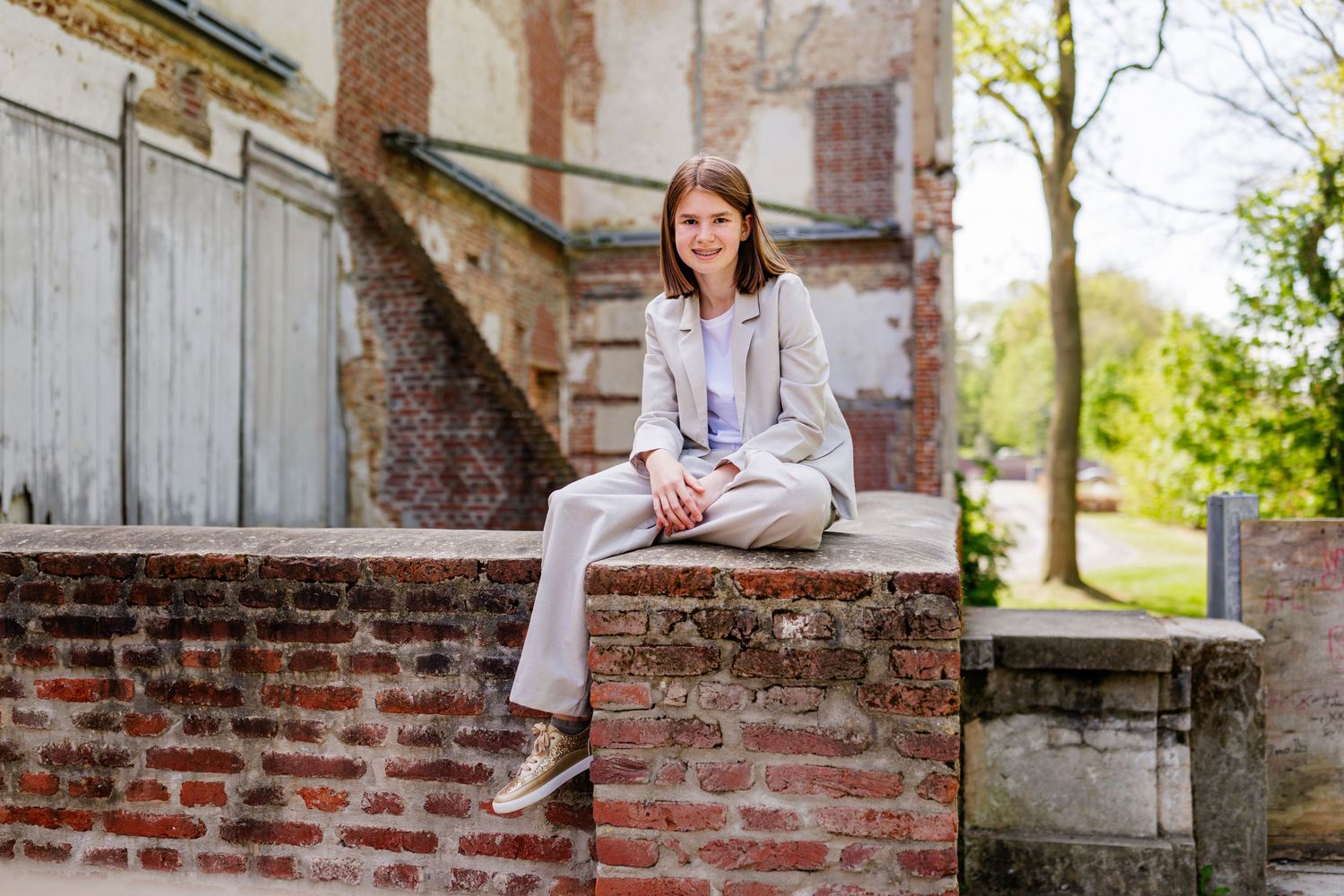 A figure in white clothing sits on rustic brick steps in a garden setting, creating a peaceful outdoor portrait.