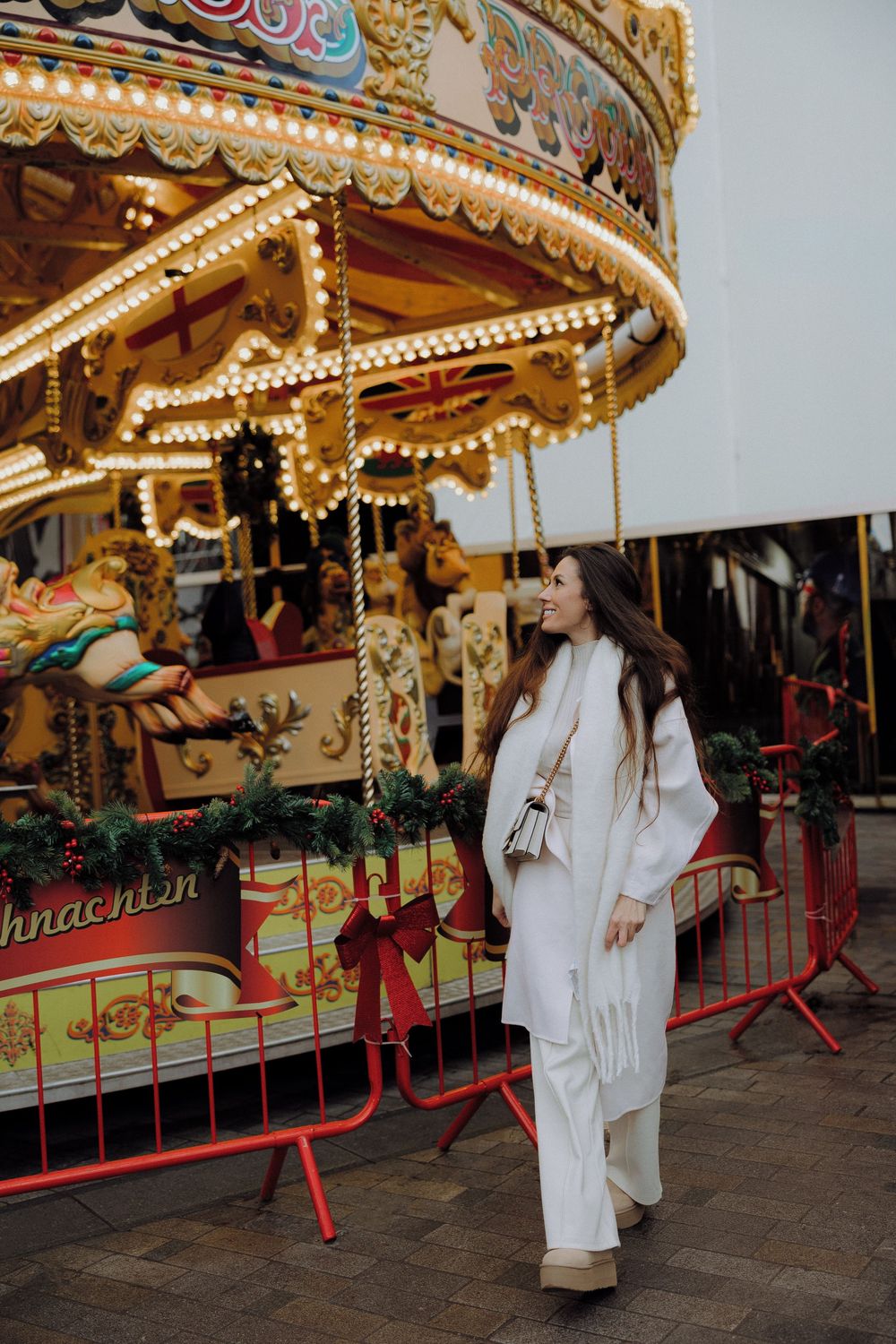 Vintage carousel with decorative lights serves as backdrop for winter fashion photography.