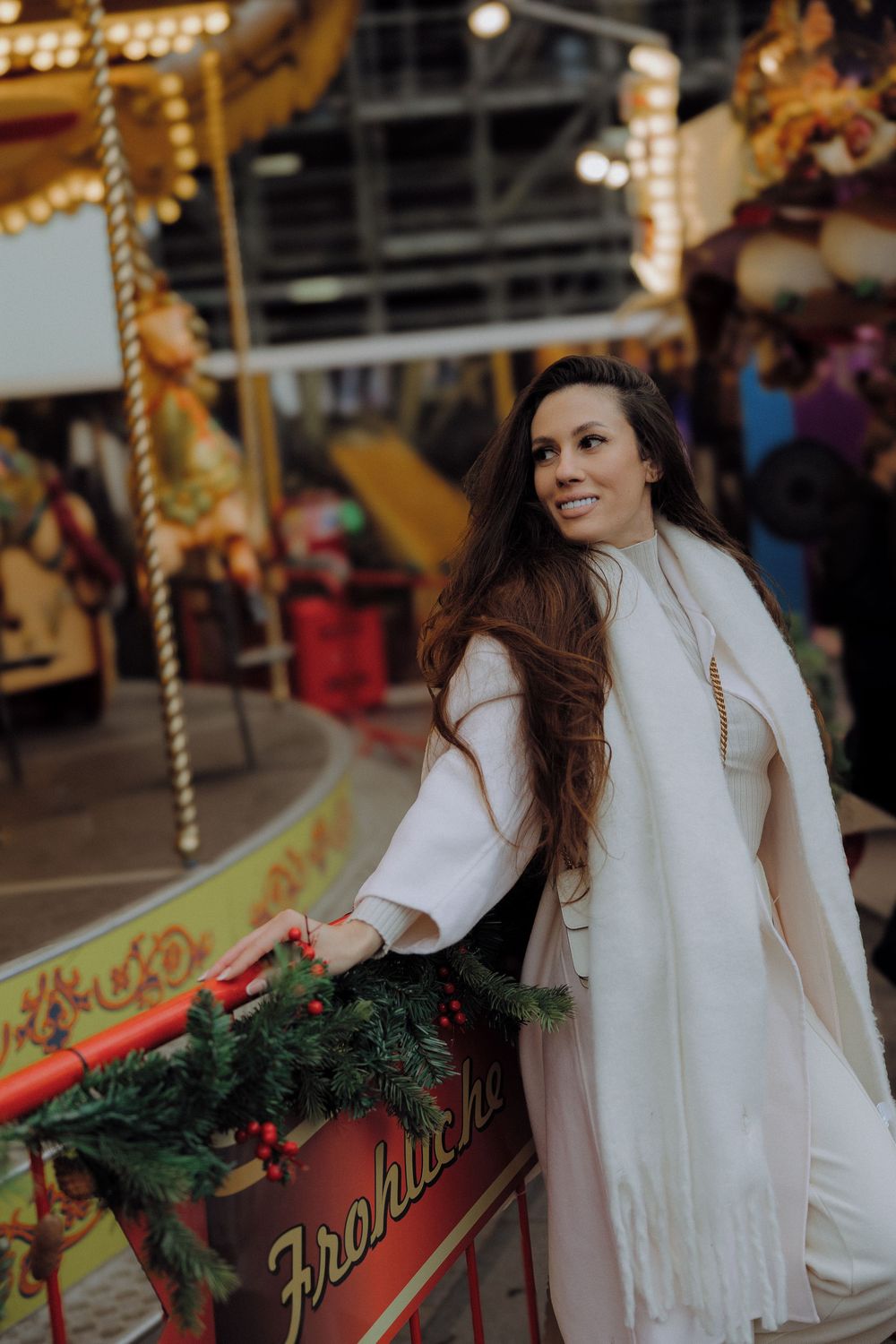 A carousel scene with holiday decorations and greenery in a festive indoor setting.