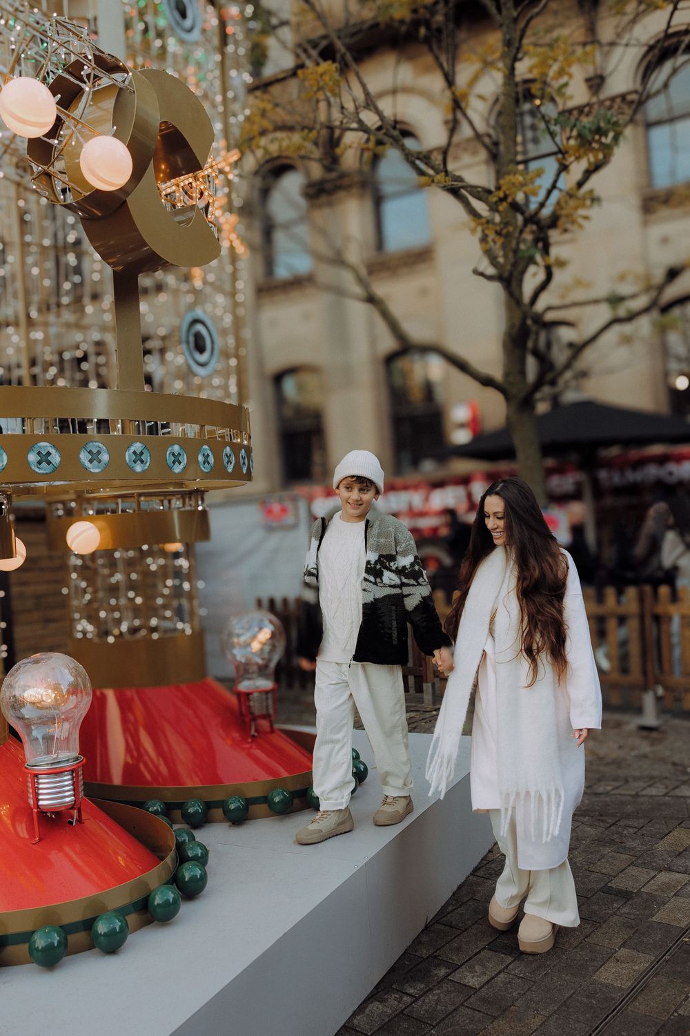 Holiday display with miniature figures on a snowy village scene with glowing lights and festive decorations.