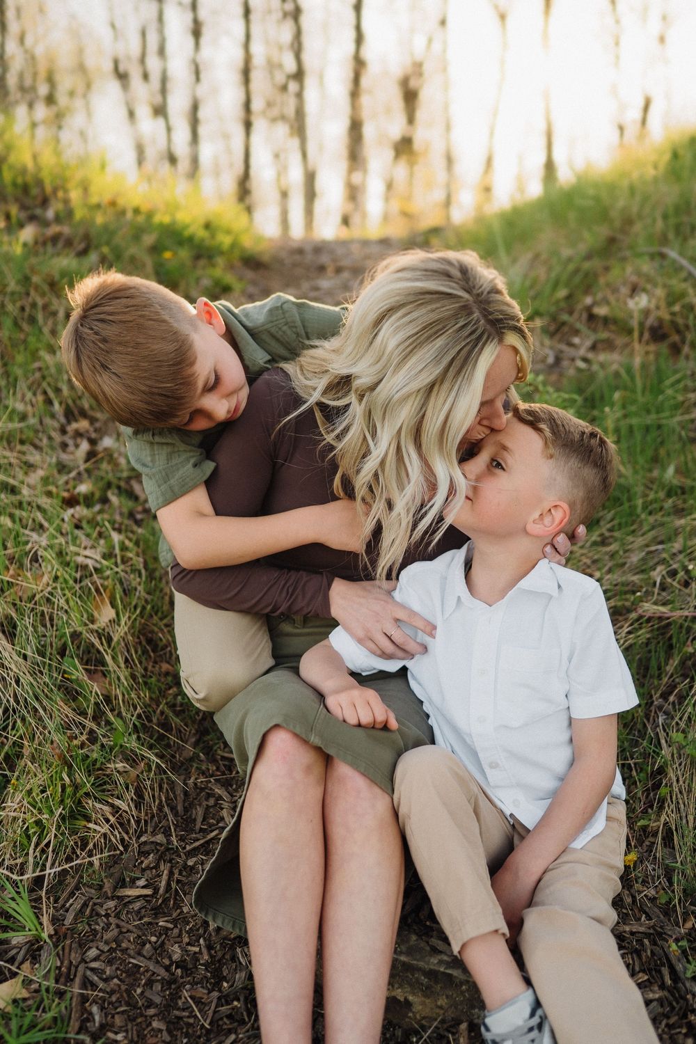 Tender family moment captured on a woodland hillside during golden hour with natural lighting.