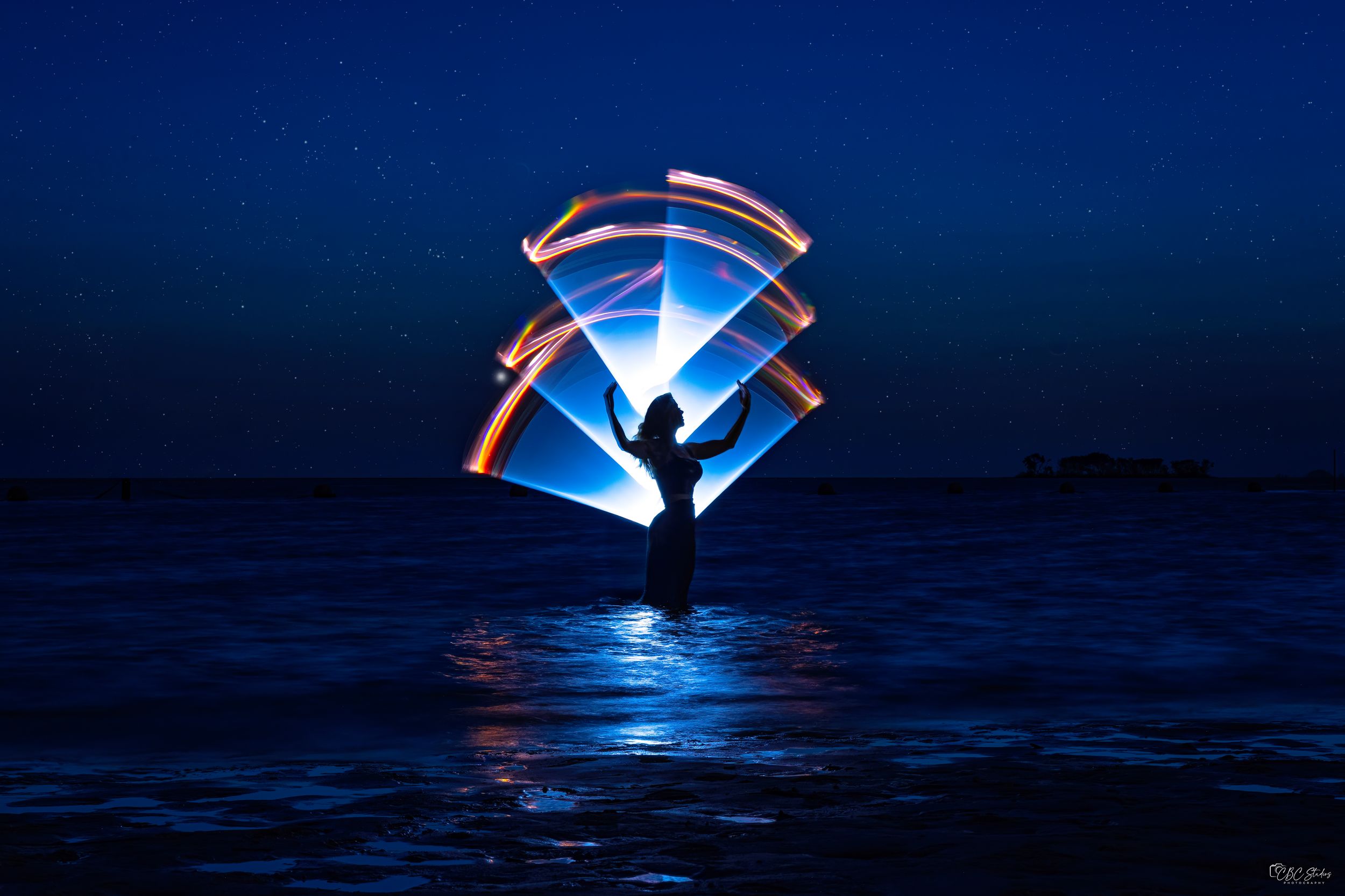 Long exposure photographs of light painting with blue LED lights against dark ocean at night creating glowing arcs.