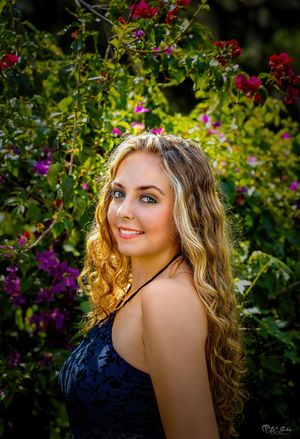 Portrait of woman in black dress against colorful garden background.