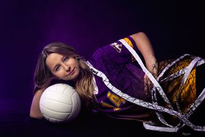 Creative volleyball portrait with player and ball against purple backdrop.
