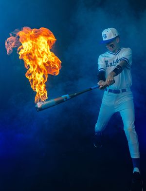 Baseball player swings bat with dramatic fire effect against blue background.