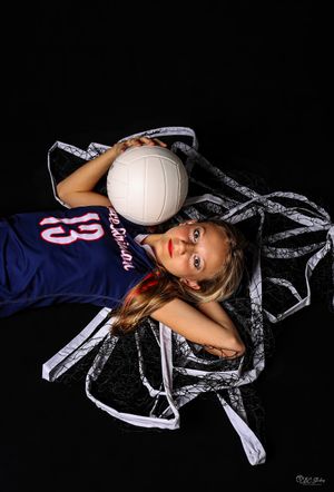 Overhead view of volleyball player lying with ball and net on black background.