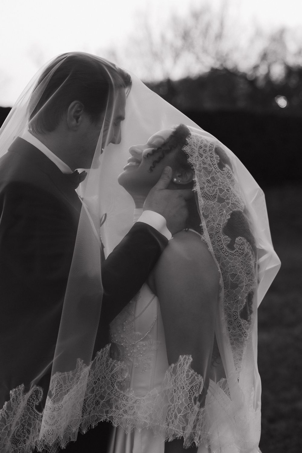 A romantic black and white photo sequence shows a couple sharing tender kisses under a delicate lace veil.