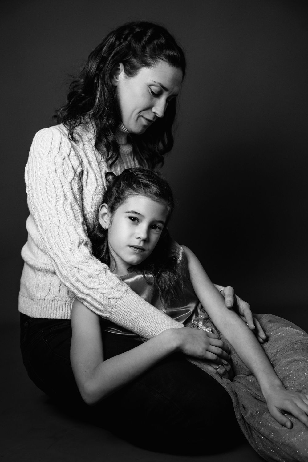 An intimate black and white portrait showing mother and daughter in a gentle embrace.