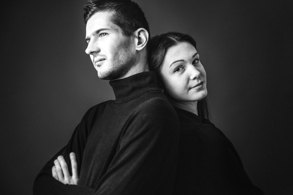 A dramatic black and white studio portrait of the siblings  back to back.