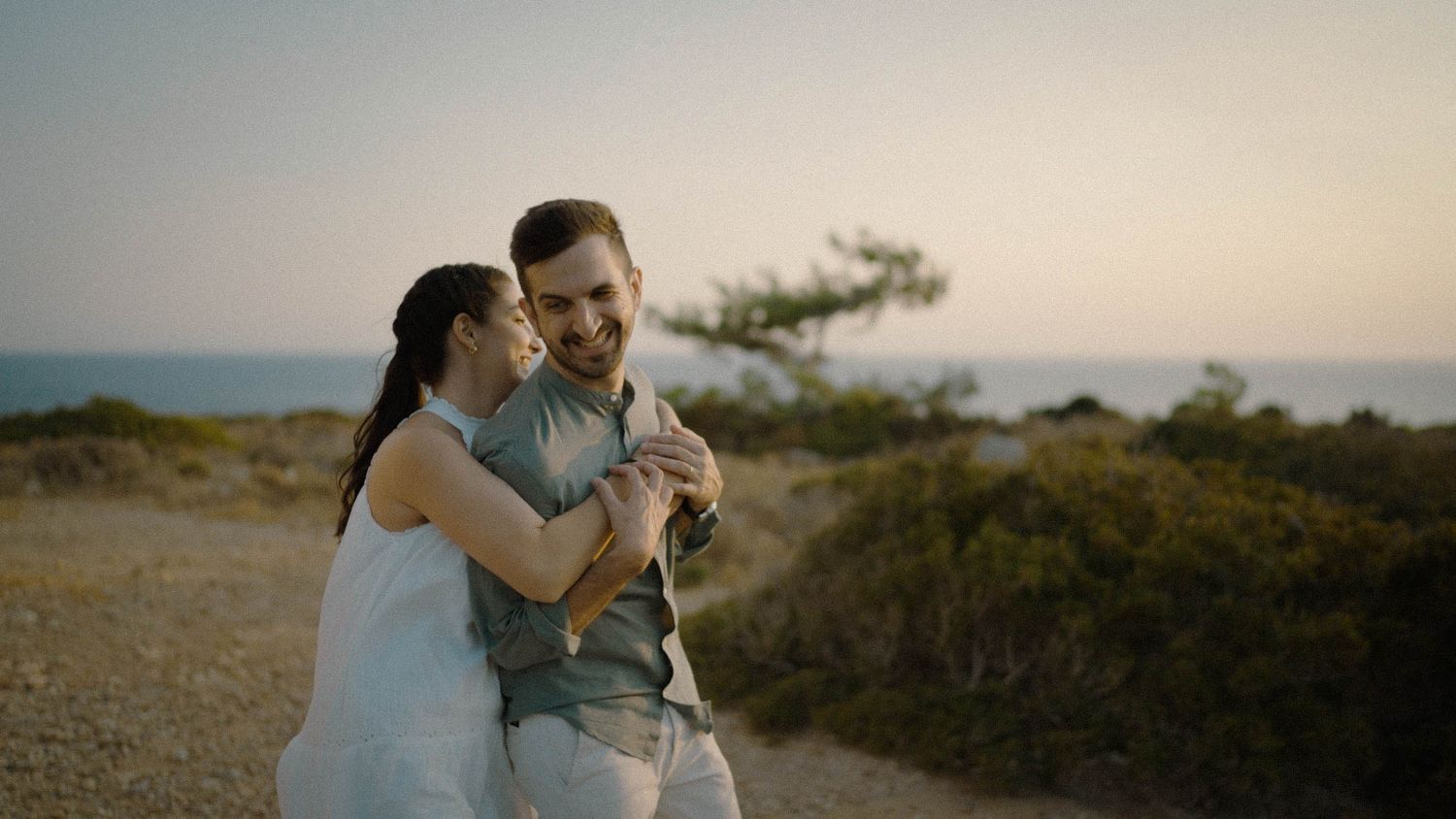 A couple walks together on a dusty hilltop path at sunset while enjoying nature and golden hour views.