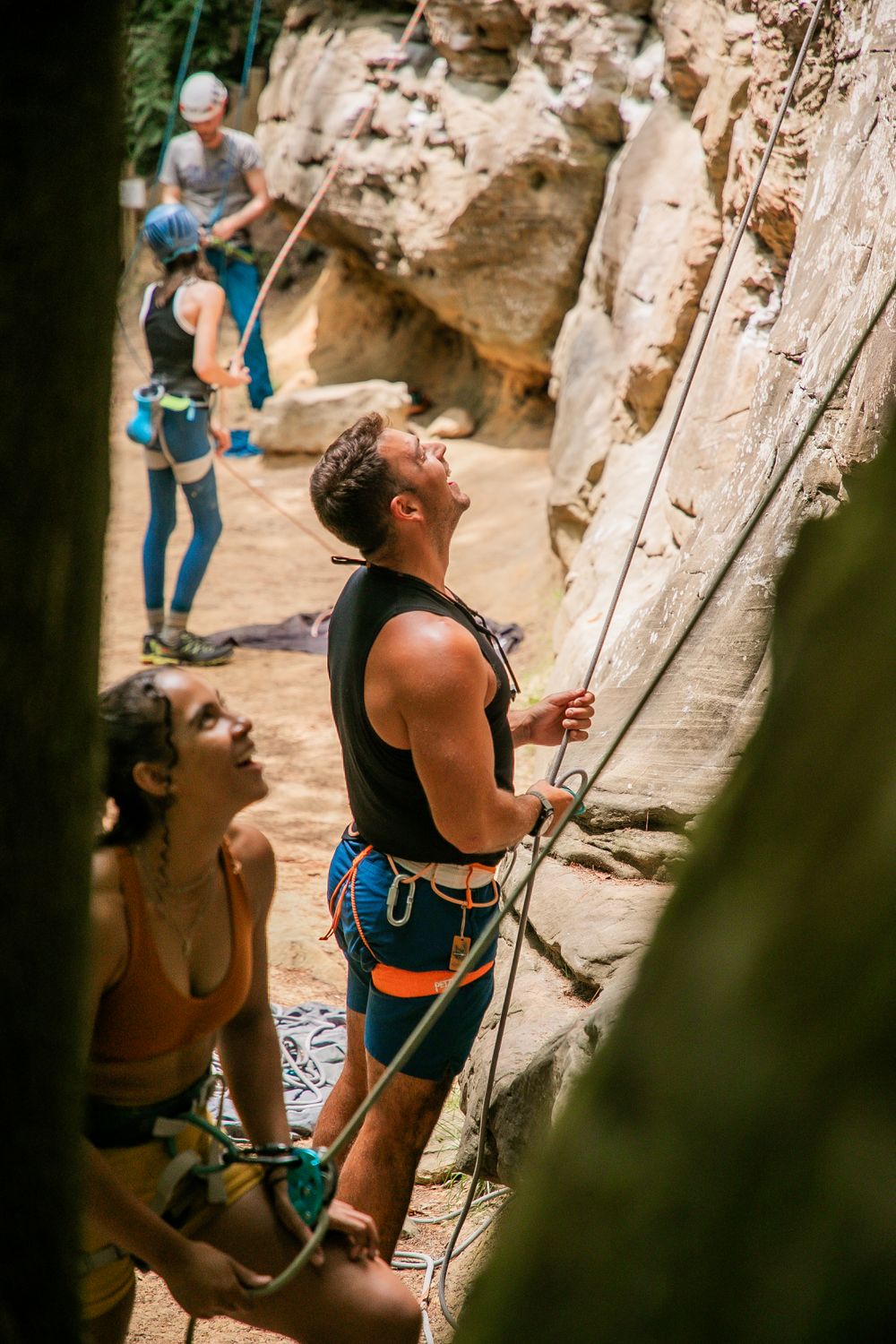 Rock climber belaying while looking up at the limestone cliff face.