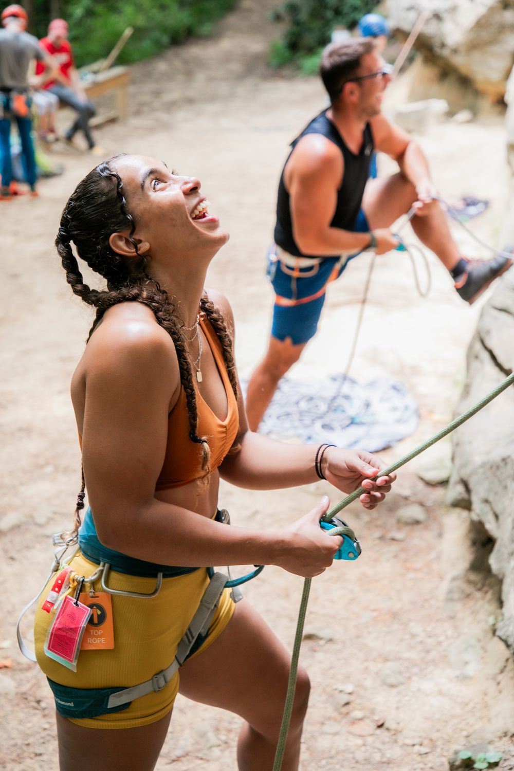 A joyful climber laughs while belaying at an outdoor climbing spot.