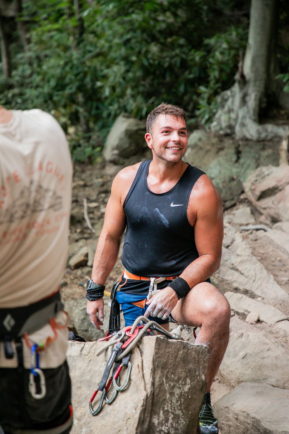 Happy climber taking a break while sitting on a rock at the crag.