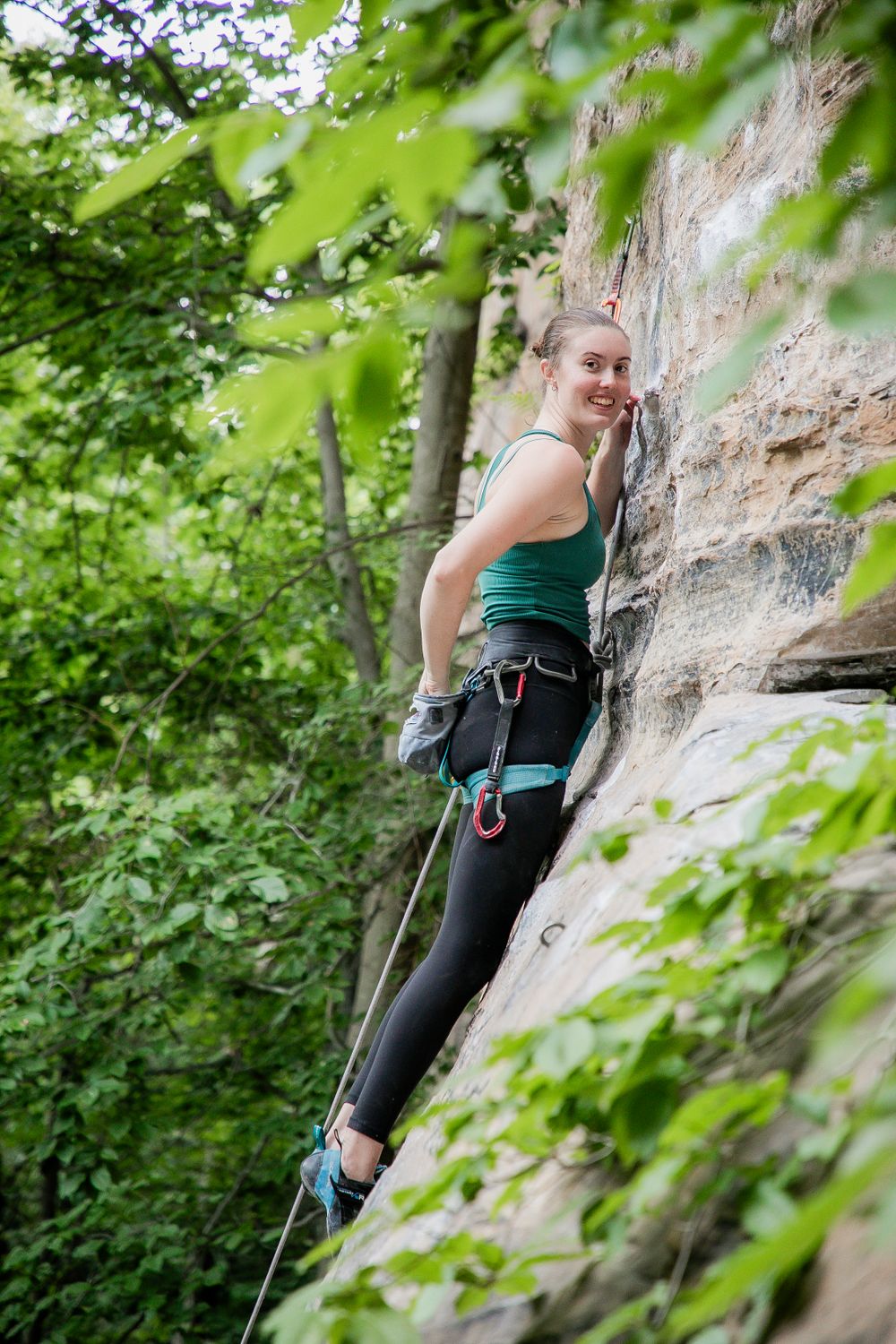 Female climber scaling a limestone wall while secured with proper climbing gear.