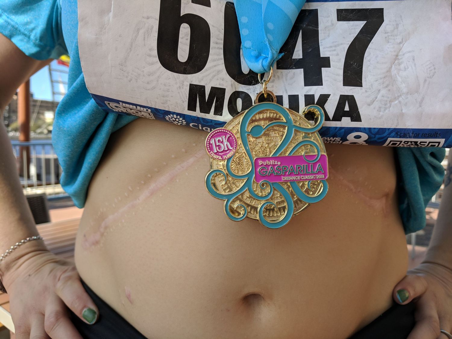A race number bib and colorful butterfly tattoo or temporary decal shown on a runner's midsection during an event.