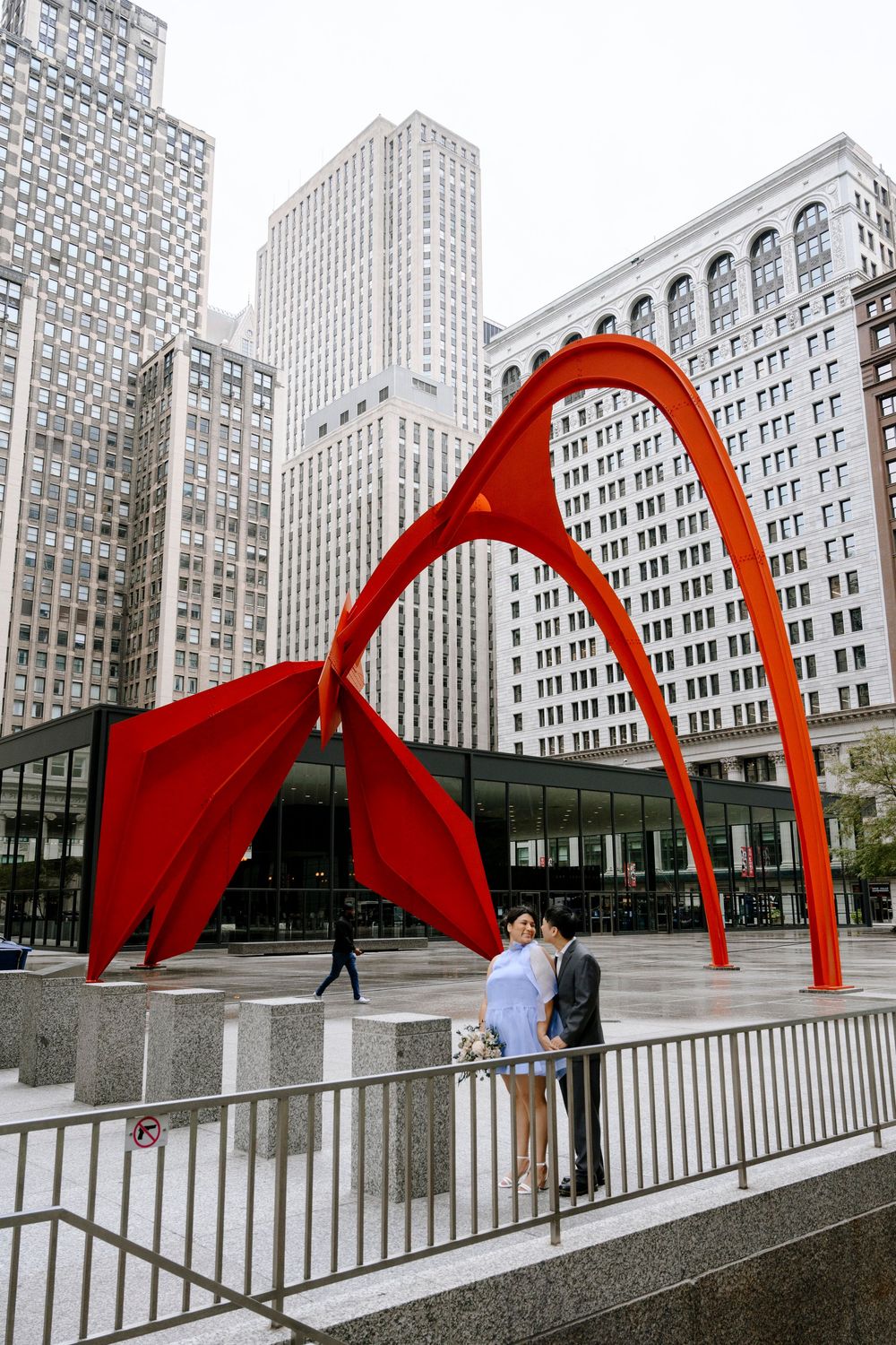 Red Calder sculpture frames urban architecture with downtown Chicago skyscrapers in background.