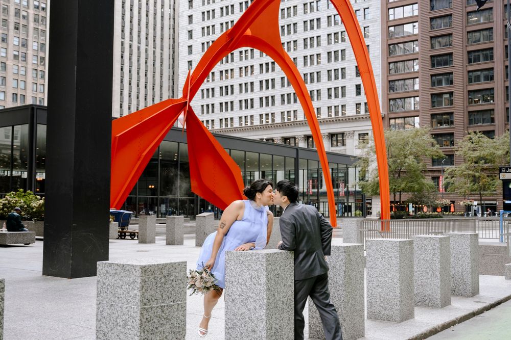 Two people stand beneath Alexander Calder's bright red-orange sculpture Flamingo in downtown Chicago's Federal Plaza.
