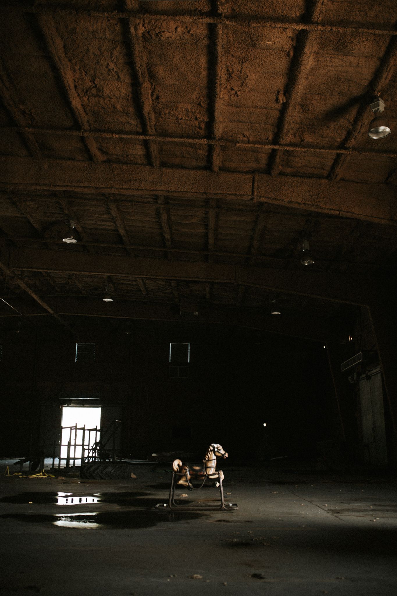 Haunting image of a rocking horse in the middle of an abandoned warehouse