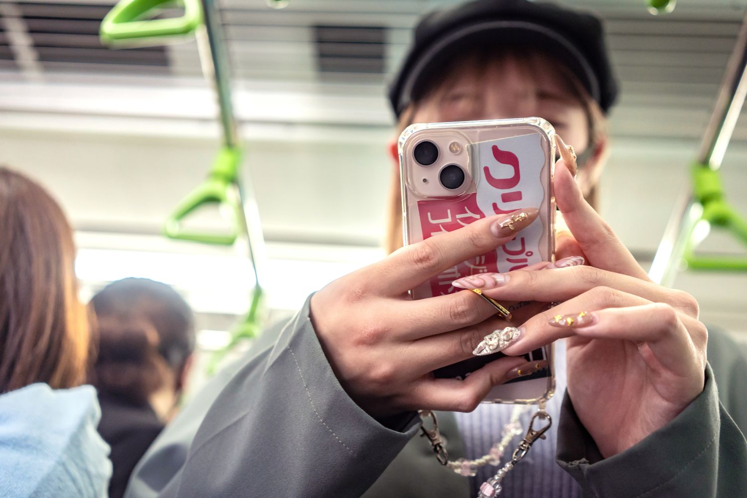Person holding a pink iPhone while riding public transportation.