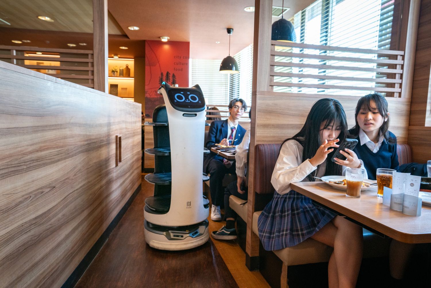 Restaurant with robot waiter serving customers at wooden tables.