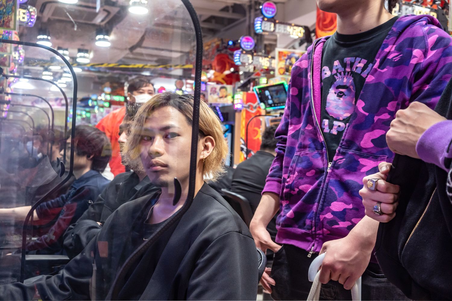 Arcade gaming scene with people in colorful clothing playing games.