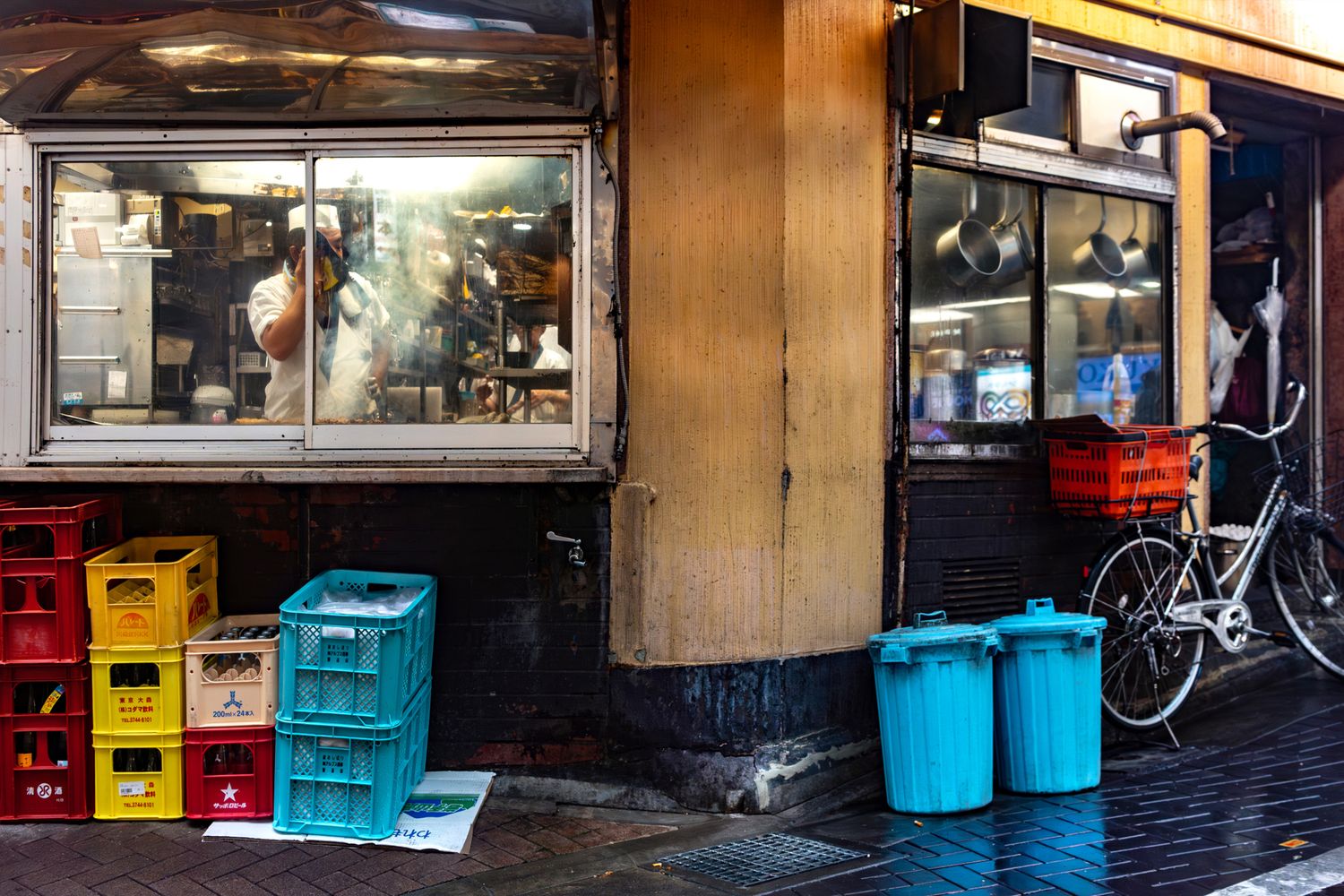 Urban storefront with blue plastic crates and a bicycle parked outside.