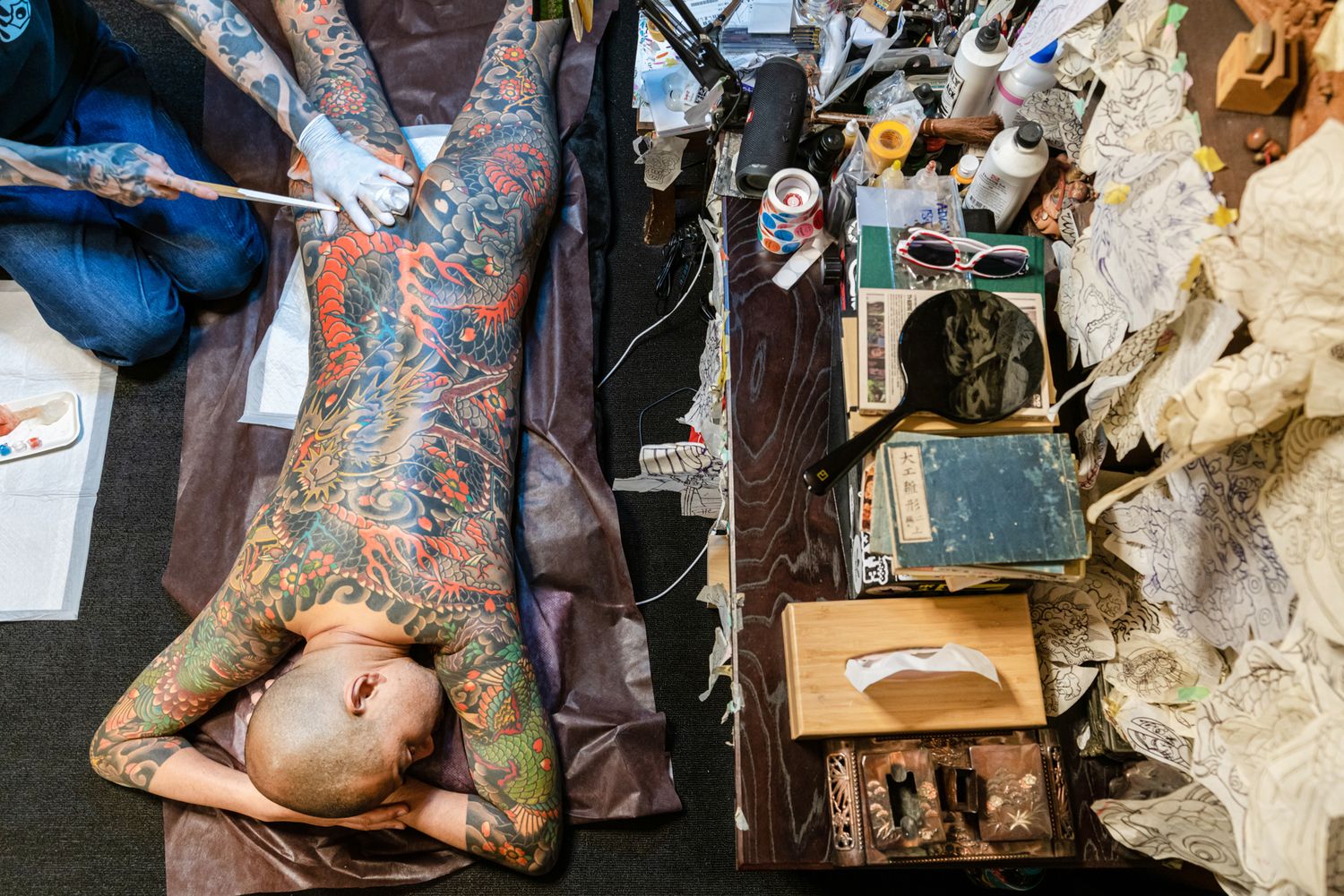 Detailed view of traditional Japanese tattoo work being performed in studio setting.