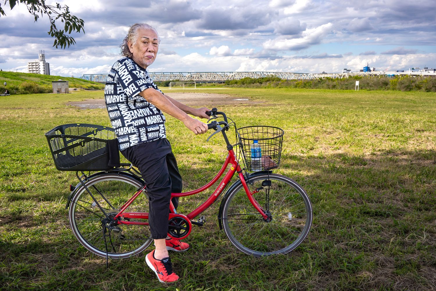 Person riding a red bicycle with basket through rural countryside.